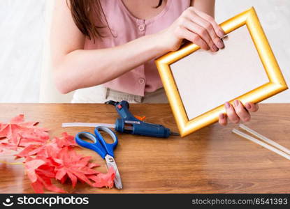 Woman decorating picture frame in scrapbooking concept