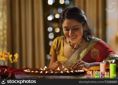 Woman decorating the house with diya on the occasion of diwali