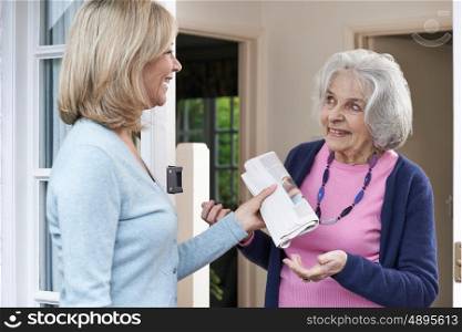 Woman Delivering Newspaper To Elderly Neighbour