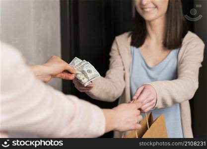 woman delivering paper bag receiving banknotes