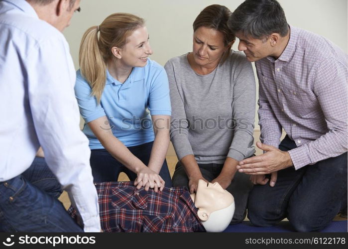 Woman Demonstrating CPR On Training Dummy In First Aid Class