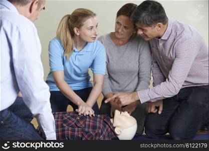 Woman Demonstrating CPR On Training Dummy In First Aid Class