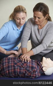 Woman Demonstrating CPR On Training Dummy In First Aid Class