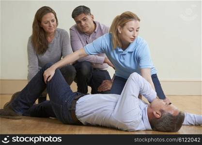 Woman Demonstrating Recovery Position In First Aid Training Class