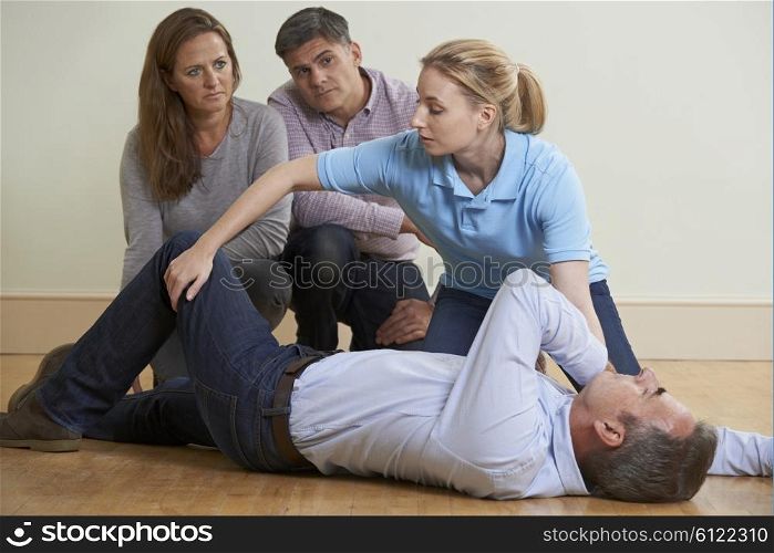Woman Demonstrating Recovery Position In First Aid Training Class