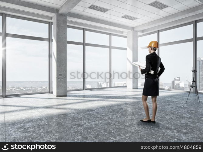 Woman designer in interior. Attractive elegant woman in helmet in modern interior. Mixed media