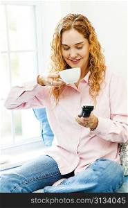 Woman dialing phone and drinking coffee