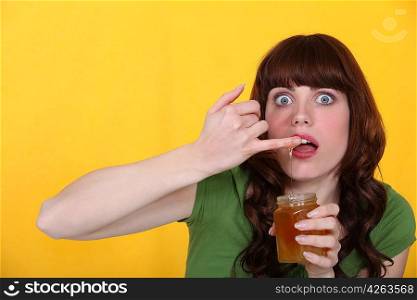 Woman dipping finger in honey jar