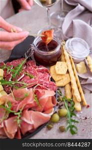 woman dips parmesan cheese into sauce, Two glasses of white wine and Italian antipasto meat platter.. woman dips parmesan cheese into sauce, Two glasses of white wine and Italian antipasto meat platter