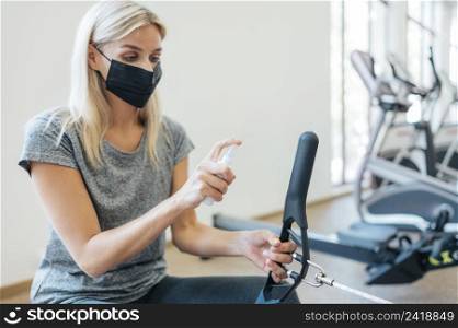 woman disinfecting gym equipment during pandemic