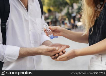 woman disinfecting her husband s hands