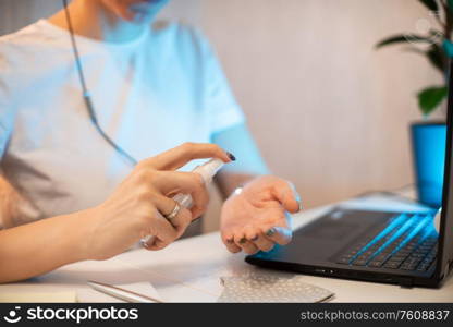 Woman disinfects the surface of the phone by sanitizer spray on the working place. Coronavirus concept. Woman in quarantine for coronavirus covid-19 working from home.. Woman disinfects the surface of the phone