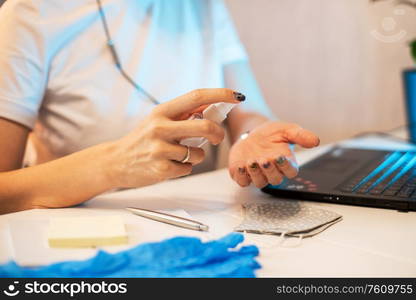 Woman disinfects the surface of the phone by sanitizer spray on the working place. Coronavirus concept.. Woman disinfects the surface of the phone