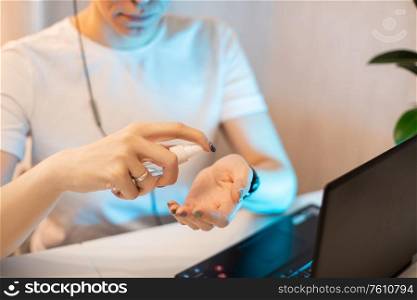 Woman disinfects the surface of the phone by sanitizer spray on the working place.. Woman disinfects the surface of the phone