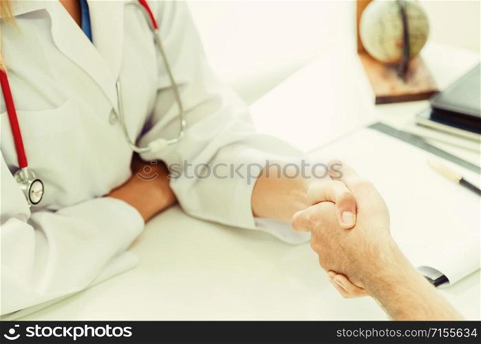 Woman doctor doing handshake with male patient in hospital office room. Healthcare and medical service occupation.