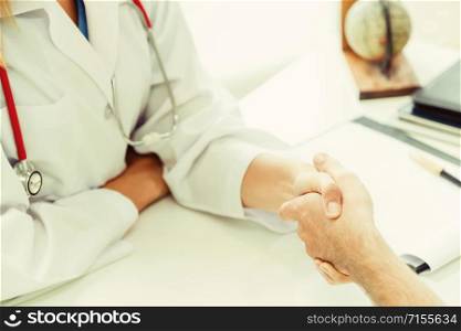 Woman doctor doing handshake with male patient in hospital office room. Healthcare and medical service occupation.