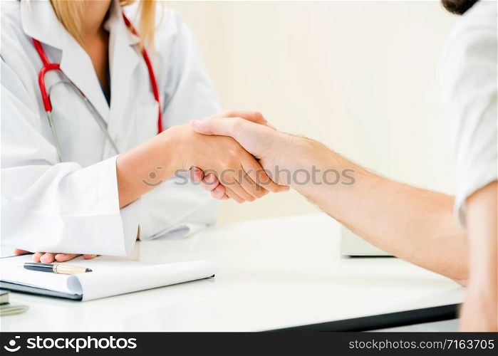 Woman doctor doing handshake with male patient in hospital office room. Healthcare and medical service occupation.. Doctor shake hand with patient in the hospital.