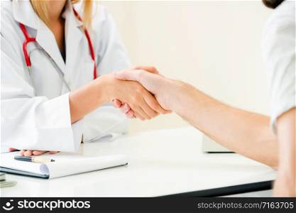 Woman doctor doing handshake with male patient in hospital office room. Healthcare and medical service occupation.. Doctor shake hand with patient in the hospital.