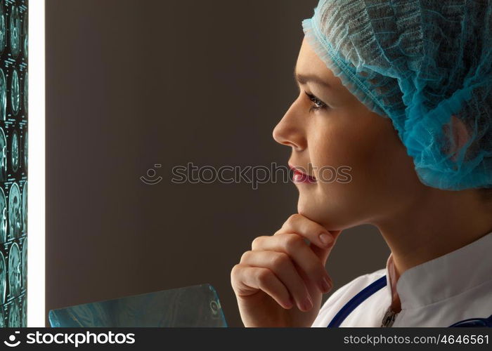 Woman doctor examining x-ray. Image of attractive woman doctor looking at x-ray results