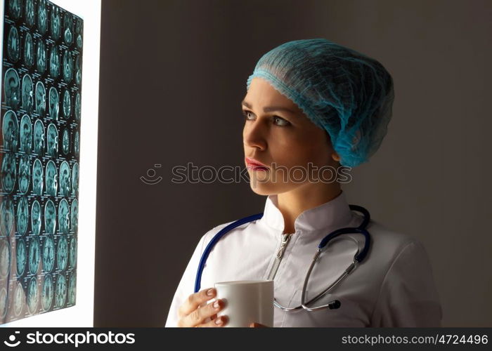 Woman doctor examining x-ray. Image of attractive woman doctor looking at x-ray results