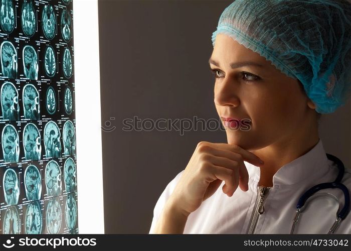 Woman doctor examining x-ray. Image of attractive woman doctor looking at x-ray results