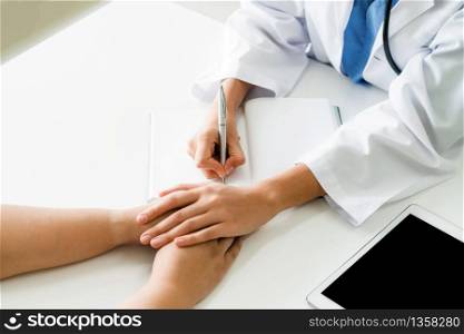 Woman doctor holds patient hand patient in room of hospital office. Healthcare and medical service.