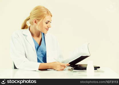 Woman doctor in hospital or healthcare institute working on medical report at office table.