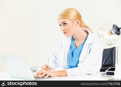 Woman doctor in hospital or healthcare institute working on medical report at office table.