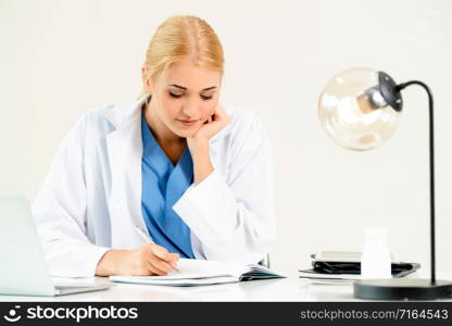 Woman doctor in hospital or healthcare institute working on medical report at office table.. Doctor in hospital working on medical report.