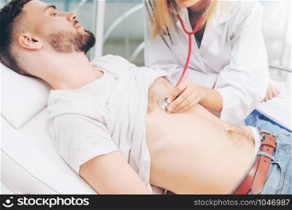 Woman doctor is examining male patient in hospital office. Healthcare and medical service.