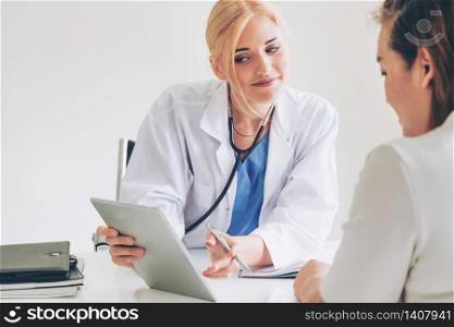 Woman doctor is talking and examining female patient in hospital office. Healthcare and medical service.. Woman Doctor and Female Patient in Hospital Office