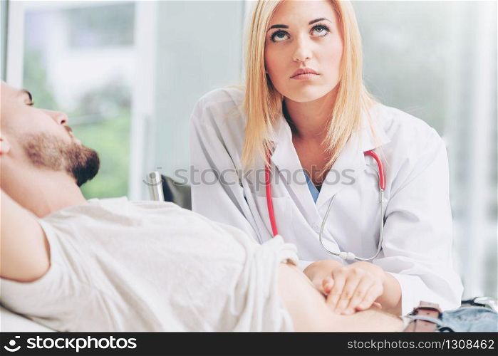 Woman doctor is talking and examining male patient in hospital office. Healthcare and medical service.. Woman Doctor and Male Patient in Hospital Office