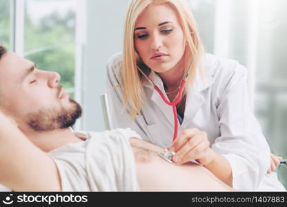 Woman doctor is talking and examining male patient in hospital office. Healthcare and medical service.. Woman Doctor and Male Patient in Hospital Office