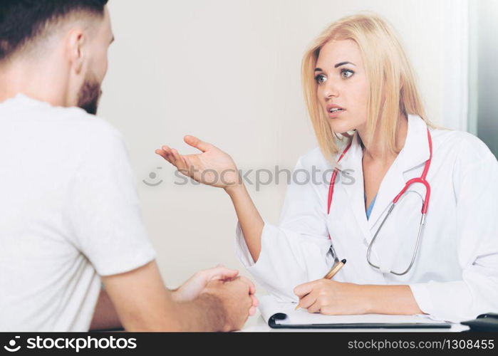 Woman doctor is talking to male patient in hospital office. Healthcare and medical service.. Woman Doctor and Male Patient in Hospital Office