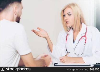 Woman doctor is talking to male patient in hospital office. Healthcare and medical service.. Woman Doctor and Male Patient in Hospital Office