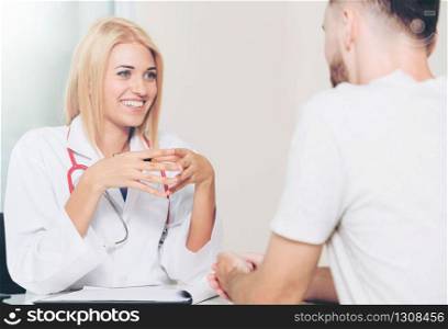 Woman doctor is talking to male patient in hospital office. Healthcare and medical service.. Woman Doctor and Male Patient in Hospital Office