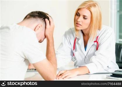 Woman doctor is talking to serious male patient in hospital office. Healthcare and medical service.. Woman Doctor and Male Patient in Hospital Office