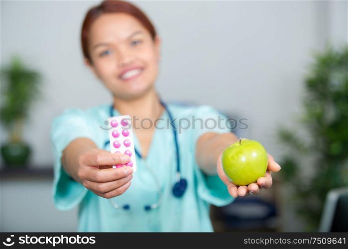 woman doctor showing tablets and an apple
