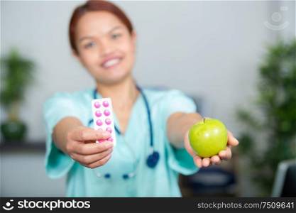 woman doctor showing tablets and an apple