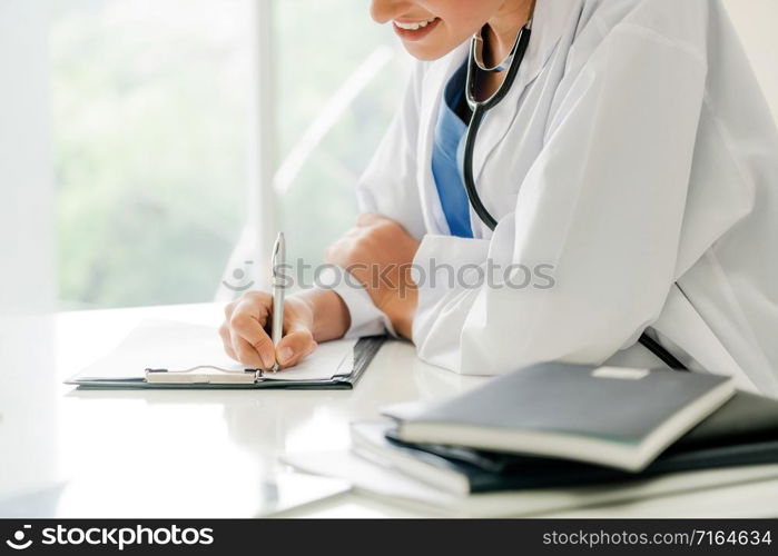 Woman doctor talks to female patient while writing on the patient health record in hospital office. Healthcare and medical service.. Woman Doctor and Female Patient in Hospital Office