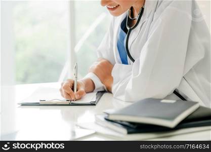 Woman doctor talks to female patient while writing on the patient health record in hospital office. Healthcare and medical service.. Woman Doctor and Female Patient in Hospital Office