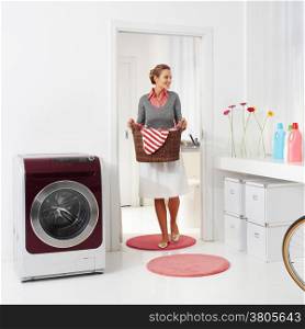 woman doing a housework holding basket of laundry