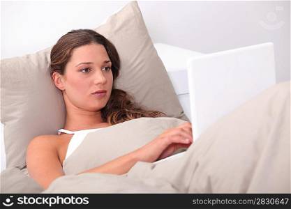 woman doing computer on her bed