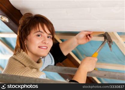 Woman doing dry walling, working under a roof slope