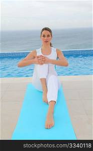 Woman doing exercises by a swimming-pool