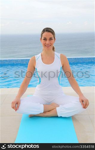 Woman doing exercises by a swimming-pool