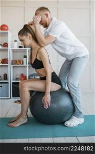 woman doing exercises with ball male physiotherapist