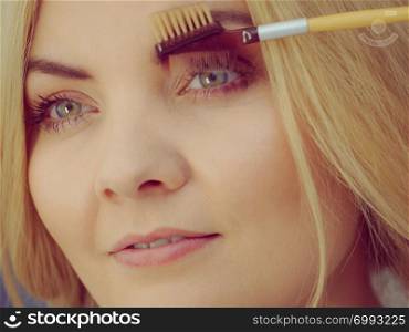 Woman doing her make up, preparing brows using brush tool brushing eyebrows.. Woman brushing her eyebrows