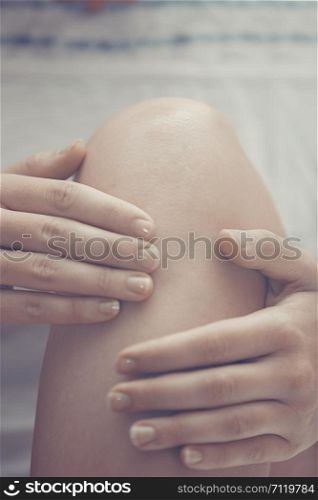 Woman doing leg massage and applying moisturizing cream