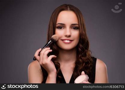 Woman doing makeup on dark background